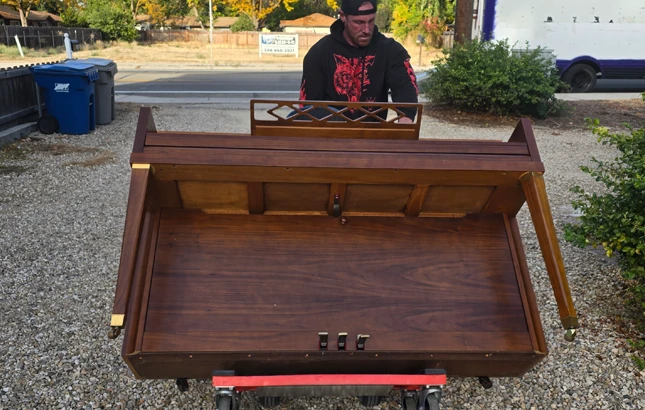 ID-Best-Moving-Company-Piano Mover moving a piano on a dolly outside a home